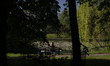 A woman with blond hair is seen on a bench in a park in front of a pond in Warsaw, Poland...