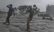 Two men are working in heavy wind during rainfall following the landfall of Cyclone Remal...