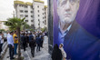 Two young women are walking past a banner featuring a portrait of Masoud Pezeshkian, a ref...