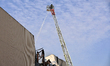 A firefighter in an aerial ladder platform is putting out a fire at a warehouse caused by...