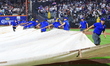 The New York Mets grounds crew is dragging the tarp on the field in the fifth inning of a...