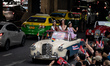 Beauty pageant queens are waving from an antique car on Sukhumvit Road in Bangkok. People...