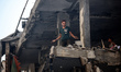 Palestinians are assessing the damage following an Israeli strike in the Nuseirat refugee...
