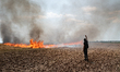 A protester is walking towards a wildfire started by a launched tear gas canister during a...