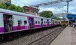 People are hanging from a train door as they are traveling in a local train in Kolkata, In...