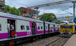 People are hanging from a train door as they are traveling in a local train in Kolkata, In...