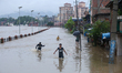 Children are wading through a flooded area on the embankments of Bagmati River in Teku, Ka...