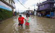 People are wading through flood water carrying their belongings and other items of necessi...