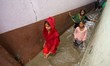 People are wading through flood water carrying their belongings and other items of necessi...