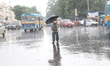 A man is crossing a busy road with an umbrella during heavy monsoon rain in Kolkata, India...
