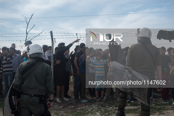 Refugees in front of a fence while police protects it in Idomeni camp, on April 7, 2016 