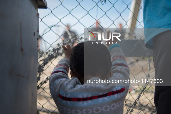 Child touching the fence of the Macedonian border. Macedonian police behind it. In Idomeni camp on April 6, 2016. 