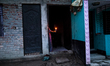 A woman of a family stands in the middle of her flood-damaged house with candles lit in th...