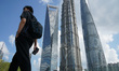 Pedestrians pass the Shanghai Tower, World Financial Center, and Jinmao Tower at Lujiazui...