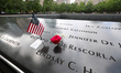Flowers and flags with photos are placed on the name panels at the reflecting pools at the...