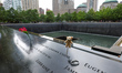 Flowers and flags with photos are placed on the name panels at the reflecting pools at the...