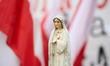 A small Virgin Mary statue is seen with Polish flags in the background in Warsaw, Poland o...