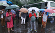 People hold umbrellas and wait for transportation in the monsoon rain in Kolkata, India, o...