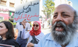 A female demonstrator raises a placard that reads in Arabic, ''The Parliament of illegitim...