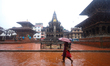 A Nepali woman wearing an umbrella walks around Patan Durbar Square, a UNESCO World Herita...