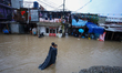 A man carries his daughter in his arms as he wades through the flooded water in Kathmandu,...
