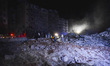 People watch as a blaze rages amid the smoldering rubble of a building destroyed in an Isr...