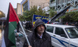 An Iranian protester holds a Palestinian flag while standing next to a vehicle carrying a...