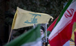 Iranian protesters wave a Lebanon's Hezbollah flag and an Iranian flag next to a portrait...