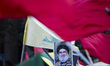 Iranian protesters wave a Lebanon's Hezbollah flag next to a portrait of Hezbollah Secreta...