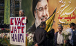 An elderly Iranian protester holds an anti-Israeli placard while standing in front of a gi...