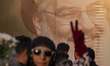 A veiled Iranian protester flashes a victory sign while standing in front of a giant banne...