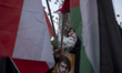 A veiled Iranian protester holds flowers and a portrait of Lebanon's Hezbollah Secretary G...