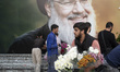 An Iranian protester holds flowers while standing in front of a giant banner depicting a p...