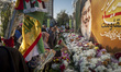 Iranian protesters place flowers under a giant banner featuring a portrait of Lebanon's He...