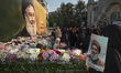 Iranian protesters place flowers under a giant banner featuring a portrait of Lebanon's He...