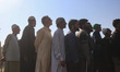 Voters queue to cast their ballots at a polling station during the third and final phase o...