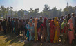 Voters queue to cast their ballots at a polling station during the third and final phase o...
