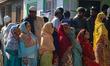 Women voters queue to cast their ballots at a polling station during the third and final p...