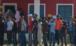 Voters queue to cast their ballots at a polling station during the third and final phase o...
