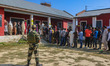 An Indian security personnel stands guard as voters queue to cast their ballots at a polli...