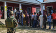 An Indian security personnel stands guard as voters queue to cast their ballots at a polli...