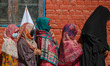 Women voters queue to cast their ballots at a polling station during the third and final p...
