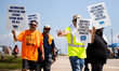 Dockworkers and their supporters hold signs during a strike outside the Bayport Container...