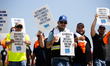 Dockworkers and their supporters hold signs during a strike outside the Bayport Container...