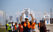 Dockworkers and their supporters hold signs during a strike outside the Bayport Container...