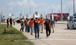 Dockworkers and their supporters hold signs during a strike outside the Bayport Container...