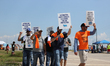 Dockworkers and their supporters hold signs during a strike outside the Bayport Container...