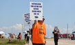 Dockworkers and their supporters hold signs during a strike outside the Bayport Container...