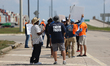 Dockworkers and their supporters hold signs during a strike outside the Bayport Container...