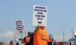 Dockworkers and their supporters hold signs during a strike outside the Bayport Container...